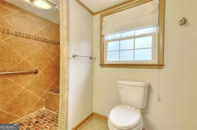 full bathroom with toilet, baseboards, ornamental molding, and a tile shower