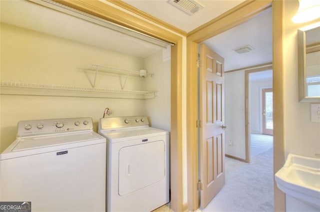 laundry room featuring light colored carpet, visible vents, a sink, laundry area, and independent washer and dryer