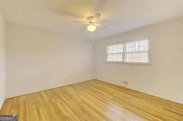 unfurnished room with ceiling fan, light wood finished floors, and visible vents