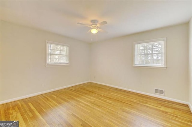 spare room with a ceiling fan, light wood-type flooring, visible vents, and baseboards