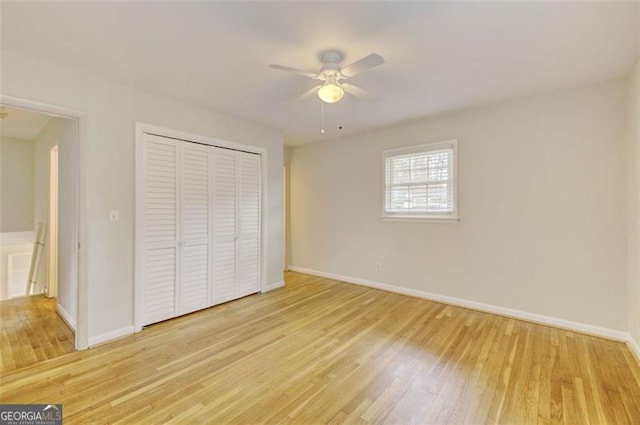 unfurnished bedroom featuring a ceiling fan, a closet, baseboards, and wood finished floors