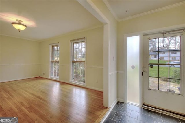 doorway featuring a healthy amount of sunlight, baseboards, ornamental molding, and wood finished floors