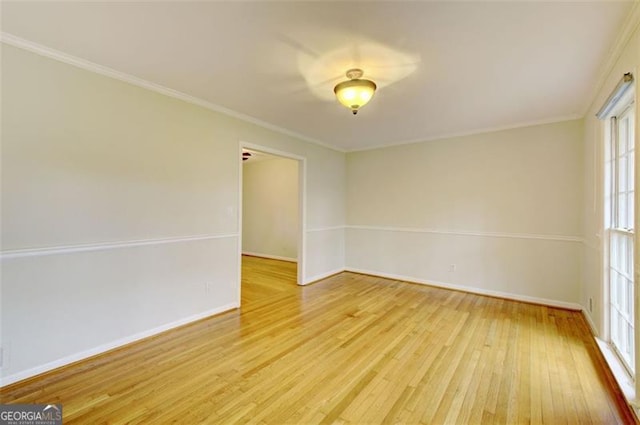 spare room featuring ornamental molding, light wood-type flooring, and baseboards