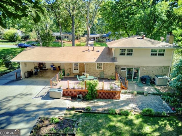 rear view of house featuring a deck, an attached carport, concrete driveway, a yard, and a chimney