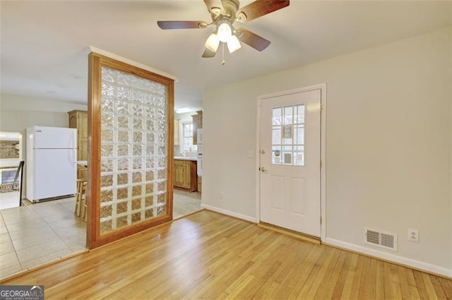 foyer with light wood-style floors, visible vents, baseboards, and a ceiling fan