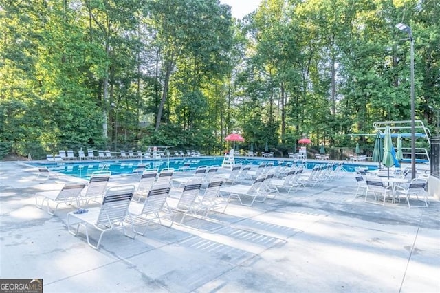 community pool with a patio area and fence