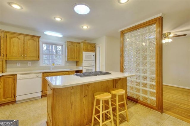 kitchen featuring light countertops, white appliances, a breakfast bar area, and a kitchen island