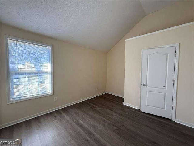 unfurnished room featuring lofted ceiling, dark wood-type flooring, and a textured ceiling