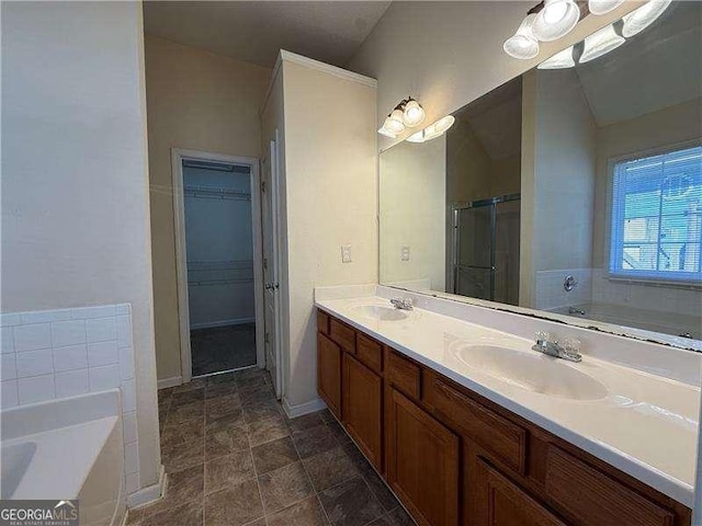 bathroom with double vanity, a stall shower, a garden tub, and a sink