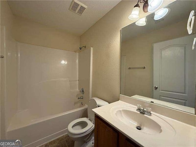 bathroom featuring a textured ceiling, a textured wall, toilet, vanity, and visible vents