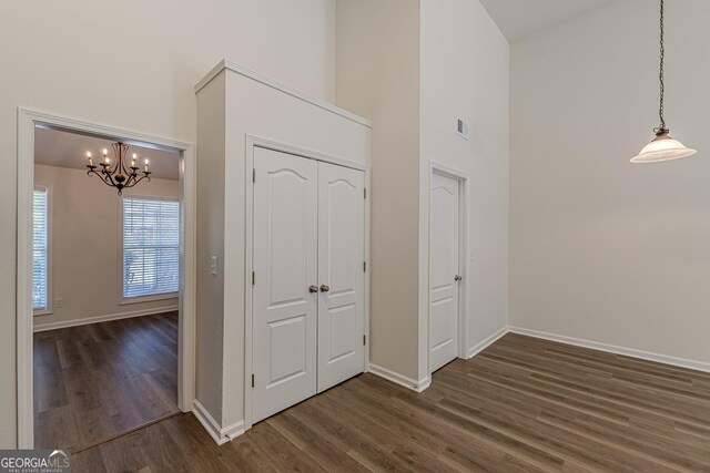 entrance foyer with a high ceiling, an inviting chandelier, visible vents, baseboards, and dark wood-style flooring