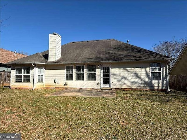 back of property featuring a yard, a patio, a chimney, and fence