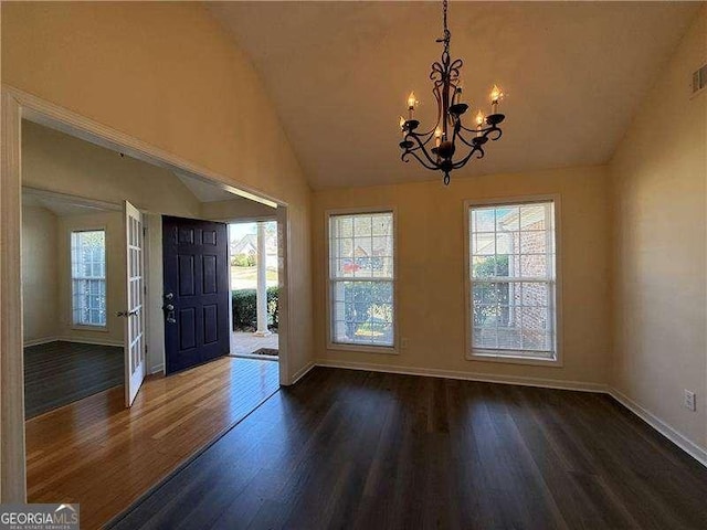 foyer featuring lofted ceiling, a notable chandelier, baseboards, and wood finished floors