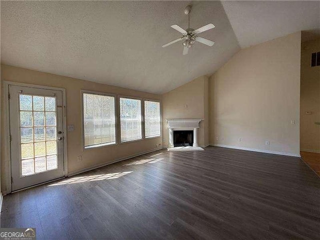 unfurnished living room featuring a fireplace with raised hearth, a textured ceiling, wood finished floors, a ceiling fan, and vaulted ceiling