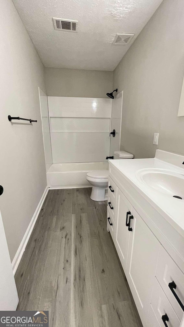 bathroom featuring visible vents, a textured ceiling, toilet, and wood finished floors