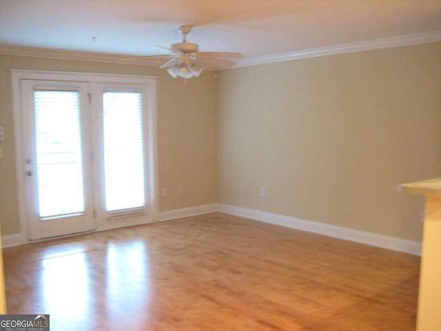 spare room with light wood-style floors, baseboards, ornamental molding, and a ceiling fan