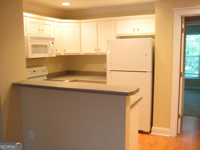 kitchen featuring white appliances, light wood finished floors, white cabinets, ornamental molding, and a peninsula