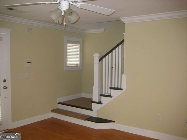 stairway with ornamental molding, wood finished floors, visible vents, and baseboards