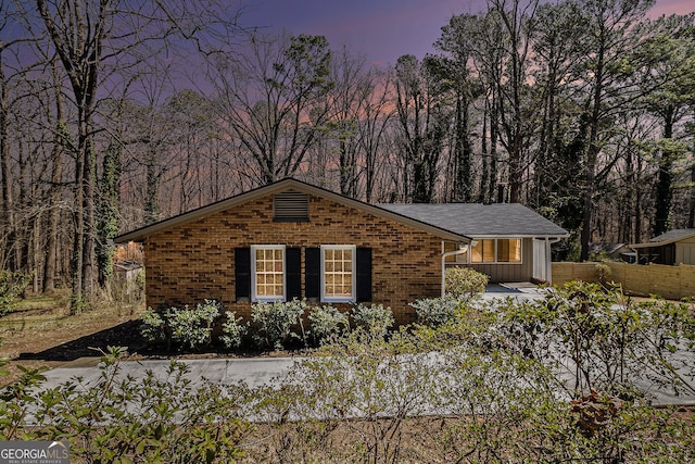 view of front facade with board and batten siding, brick siding, and fence