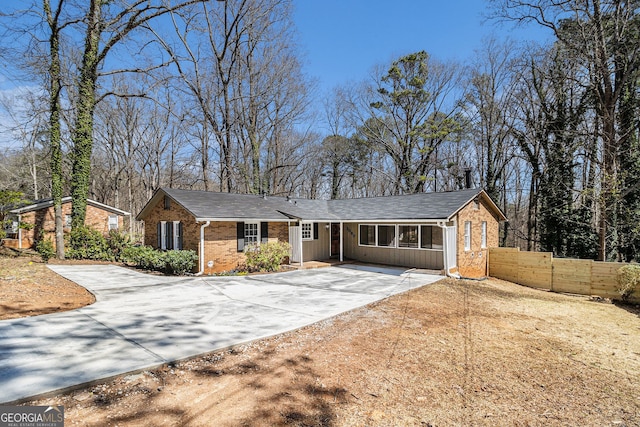 single story home with driveway, brick siding, and fence