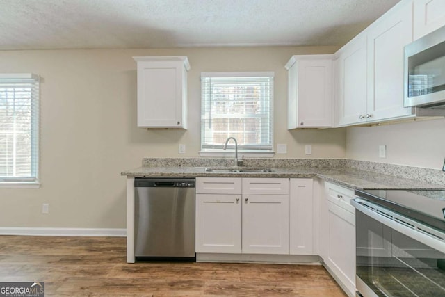 kitchen featuring stainless steel appliances, a sink, a wealth of natural light, and white cabinets