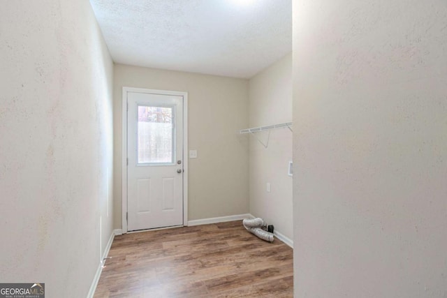 clothes washing area with laundry area, baseboards, a textured wall, wood finished floors, and a textured ceiling