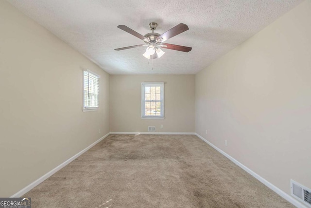 carpeted spare room with baseboards, visible vents, and a textured ceiling