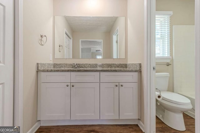 bathroom featuring a shower, toilet, vanity, a textured ceiling, and baseboards