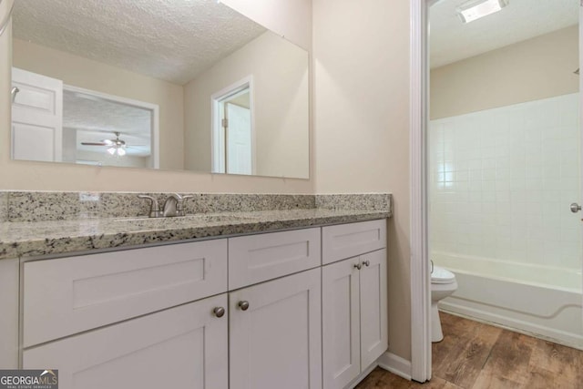 bathroom featuring toilet, vanity, a textured ceiling, and wood finished floors