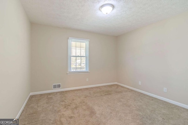 empty room with baseboards, visible vents, a textured ceiling, and carpet flooring