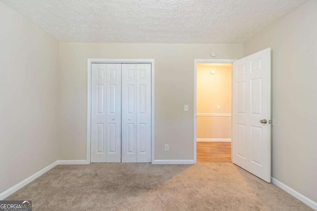 unfurnished bedroom with a closet, carpet flooring, a textured ceiling, and baseboards