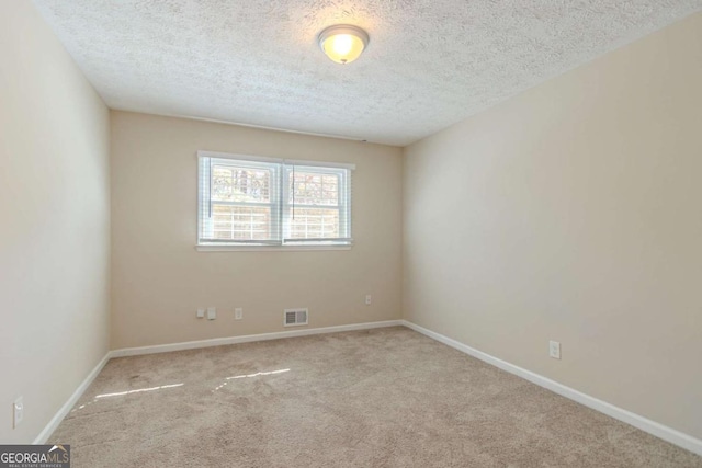 carpeted empty room with visible vents, a textured ceiling, and baseboards