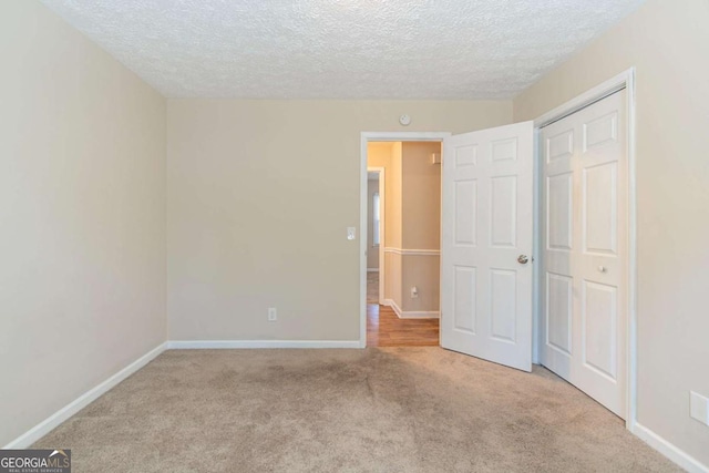 unfurnished bedroom featuring a textured ceiling, a closet, baseboards, and carpet flooring