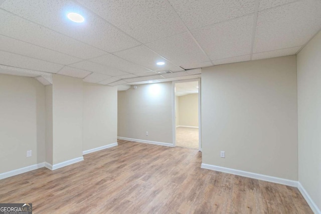 finished basement featuring a paneled ceiling, baseboards, and wood finished floors