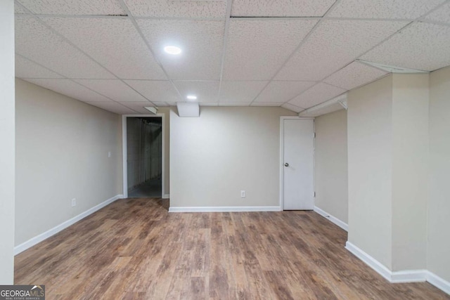 finished basement featuring wood finished floors, a paneled ceiling, and baseboards