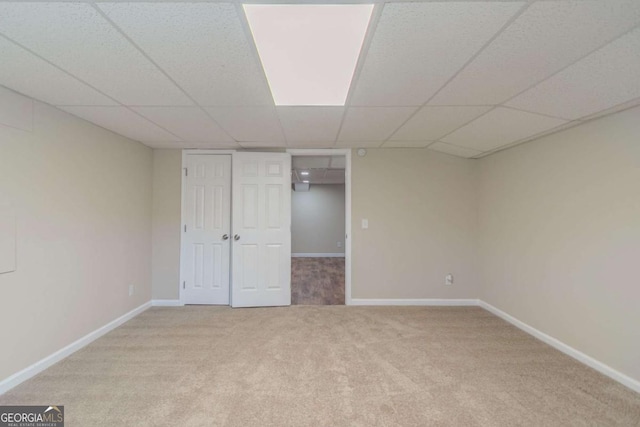 unfurnished bedroom featuring carpet, a drop ceiling, and baseboards