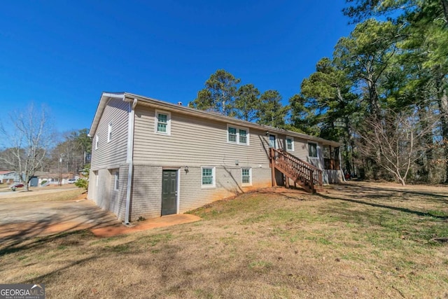 back of house with stairs and a yard