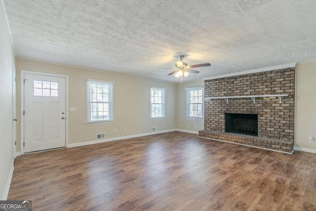 unfurnished living room featuring a brick fireplace, visible vents, baseboards, and wood finished floors