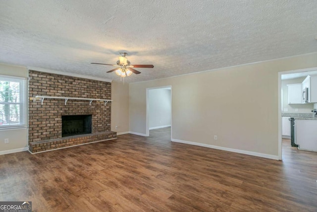 unfurnished living room with ceiling fan, a fireplace, baseboards, and wood finished floors