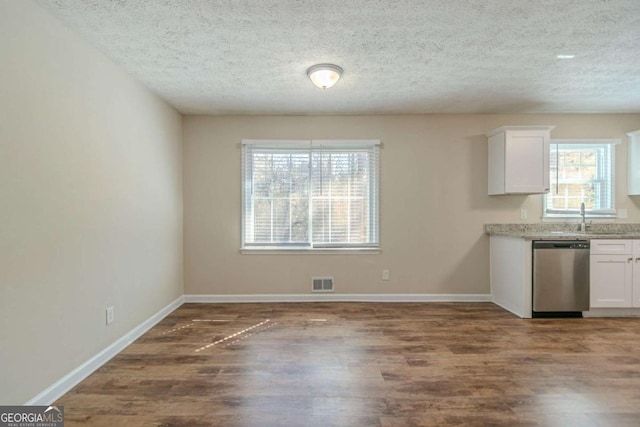 kitchen with wood finished floors, visible vents, stainless steel dishwasher, and white cabinetry