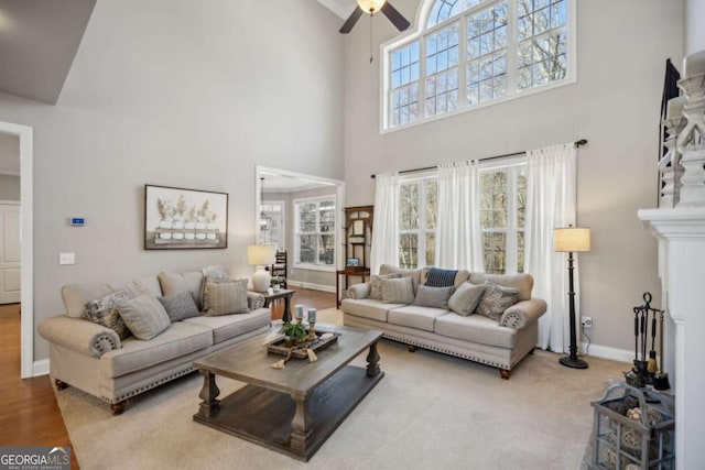 living area featuring wood finished floors, baseboards, ceiling fan, and a fireplace