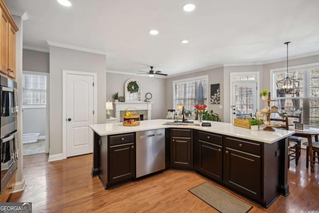 kitchen featuring light countertops, a warm lit fireplace, light wood-style flooring, and appliances with stainless steel finishes