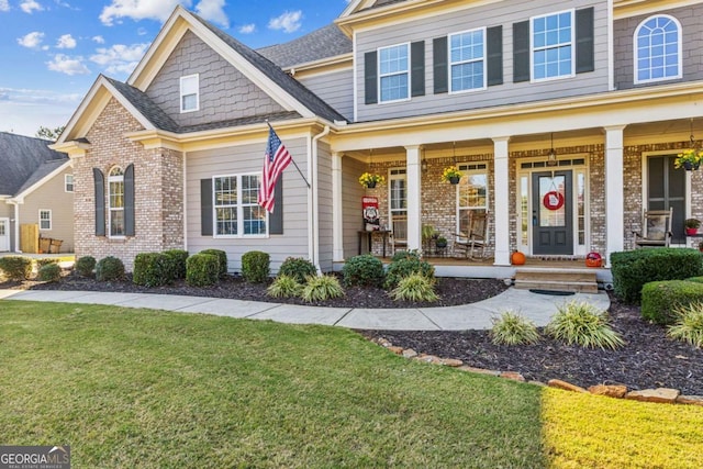 view of front of home with brick siding, covered porch, and a front lawn