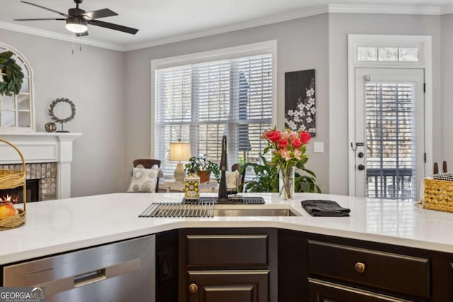 kitchen featuring ornamental molding, a brick fireplace, light countertops, and stainless steel dishwasher