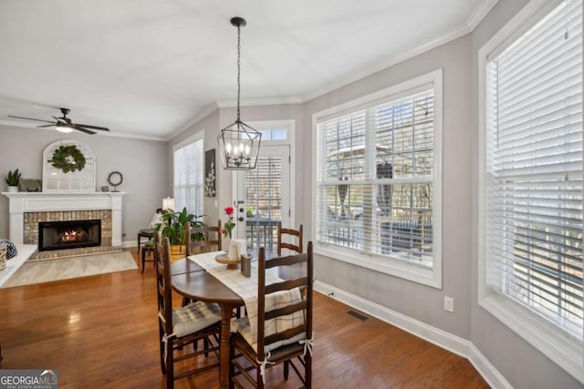 dining room featuring baseboards, wood finished floors, visible vents, and ornamental molding