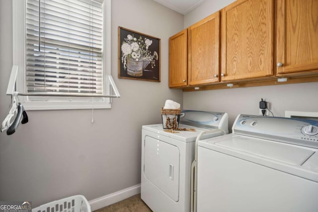 clothes washing area with washing machine and clothes dryer, cabinet space, and baseboards