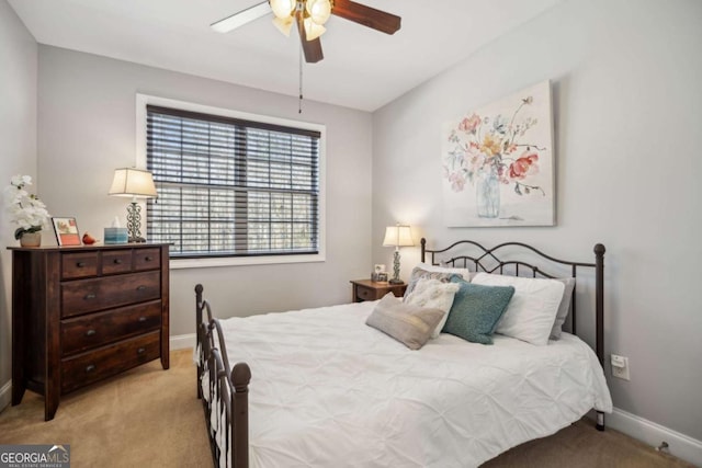 bedroom featuring baseboards, light colored carpet, and ceiling fan