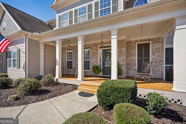 doorway to property featuring brick siding and covered porch