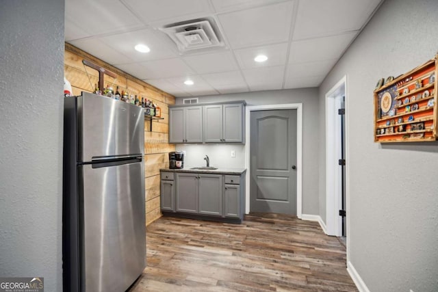 kitchen with visible vents, gray cabinetry, freestanding refrigerator, wood finished floors, and a sink