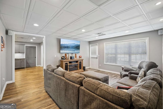 living room featuring recessed lighting, baseboards, light wood-style floors, and a glass covered fireplace